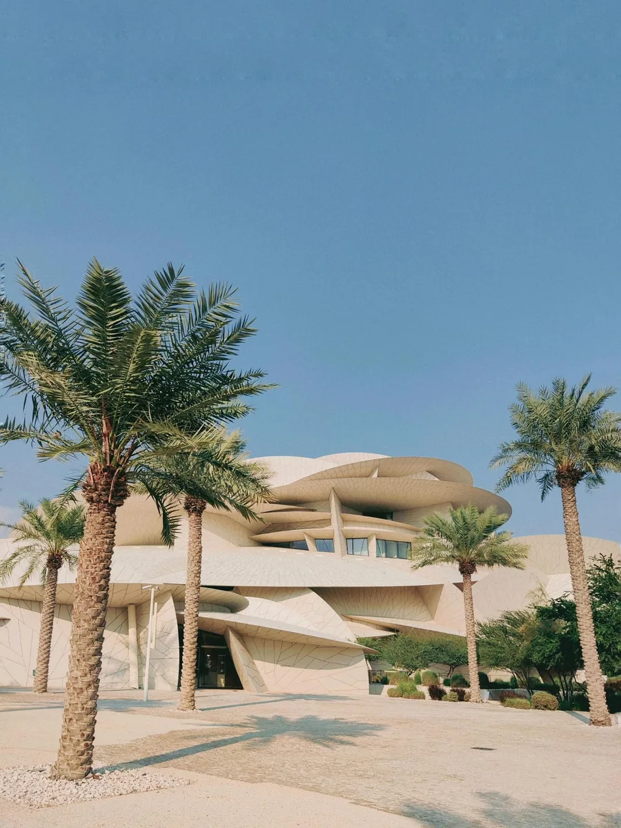 Moderne helle Architektur mit Palmen unter blauem Himmel in Doha